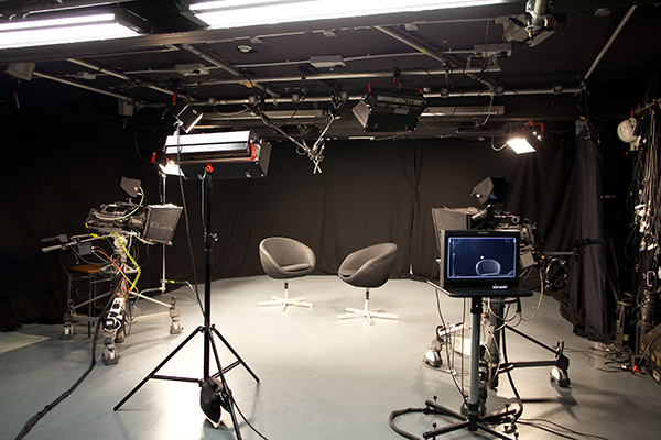Professional TV studio setup with sleek black backdrop for interviews and panel discussions.