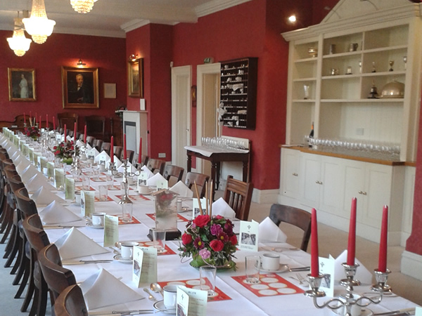 Villiers Suite dining room set for elegant events with floral centerpieces and red walls.