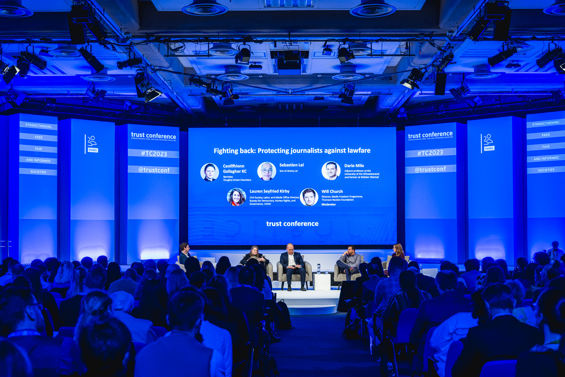 Conference panel discussion at QEII Centre with modern tech and engaged audience.