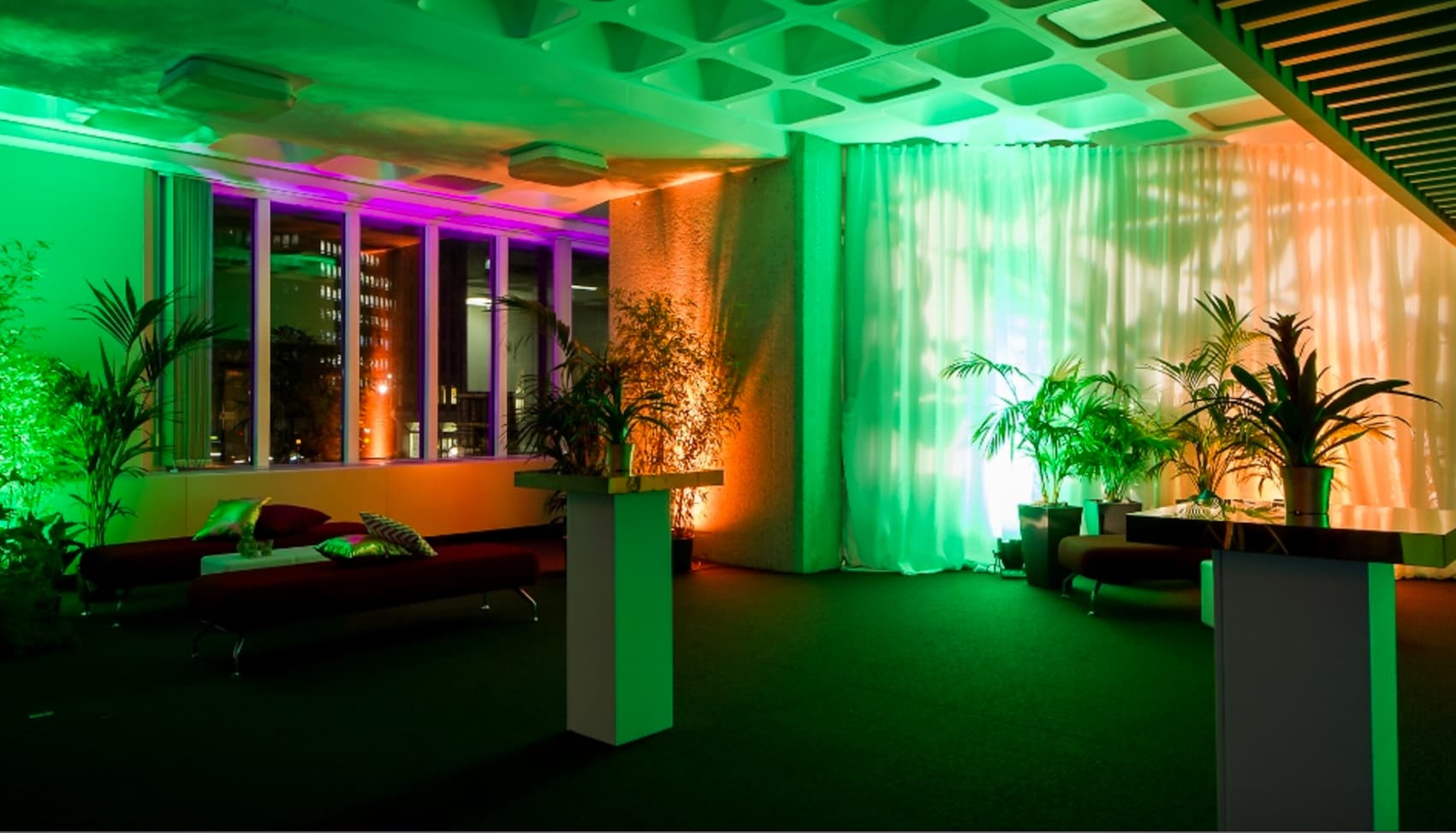 Stylish event space at QEII Centre with ambient green and purple lighting for networking events.