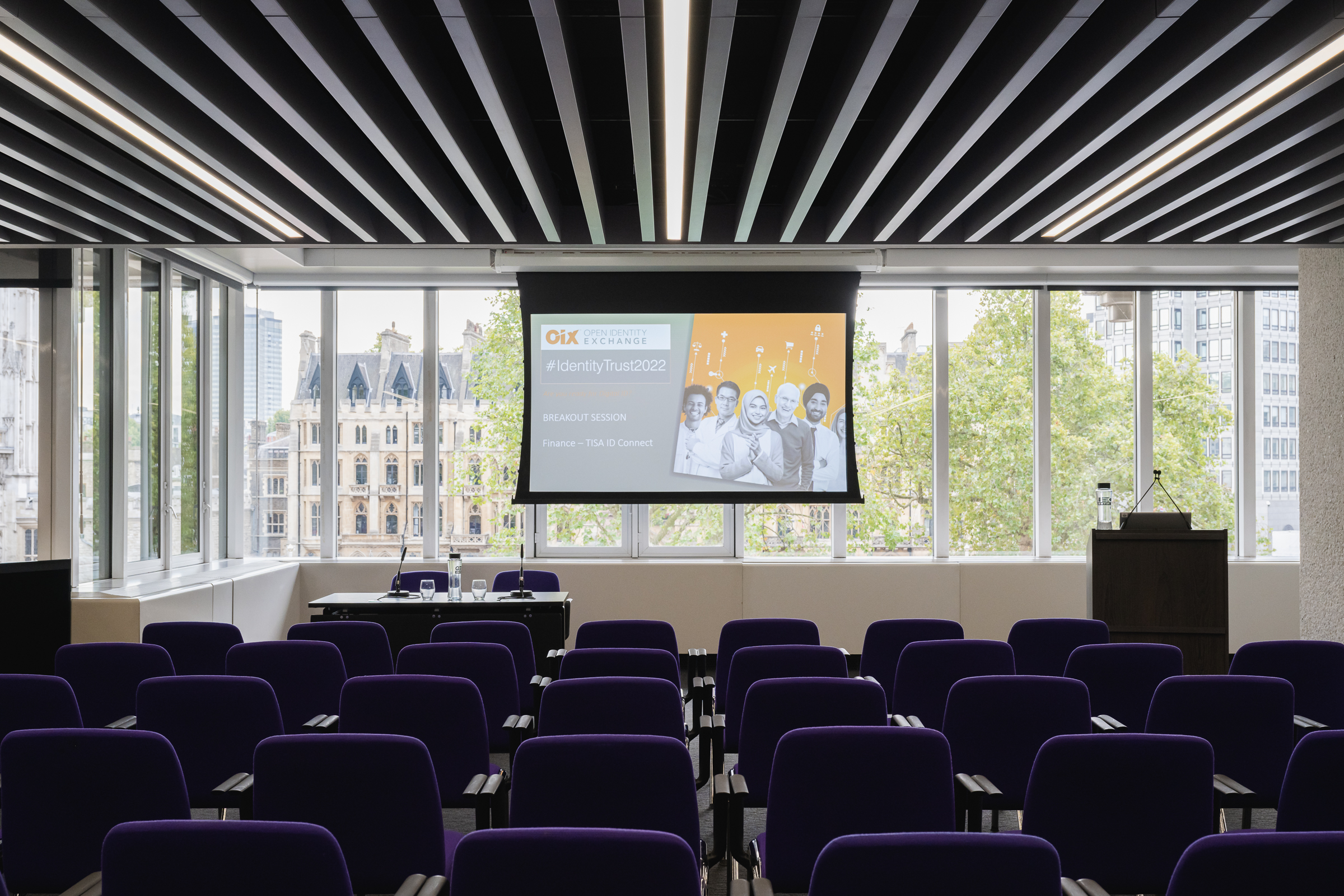 Olivier in modern QEII Centre meeting room with purple chairs for a conference presentation.