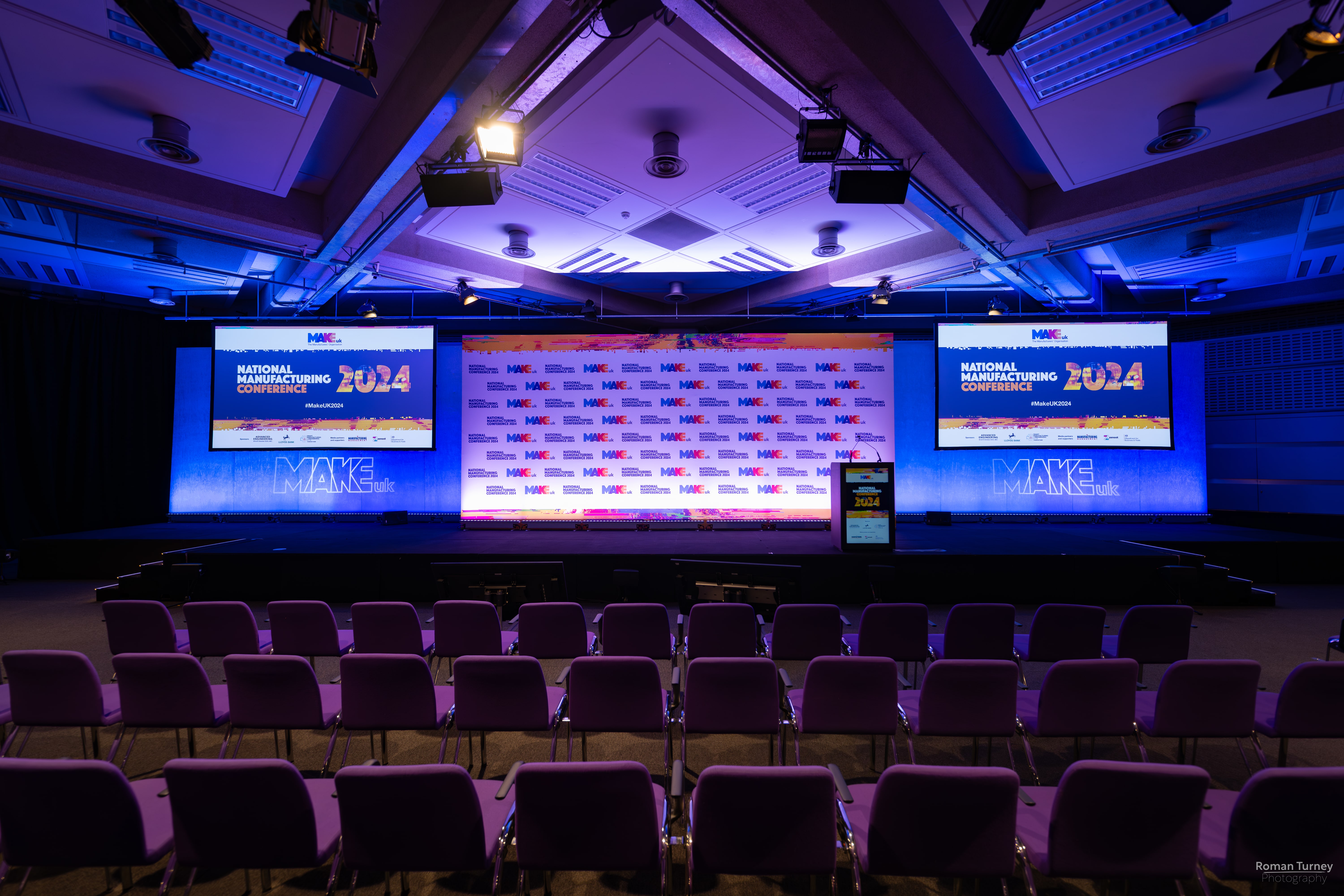 Event space with stage and dual screens, ideal for corporate meetings and conferences.