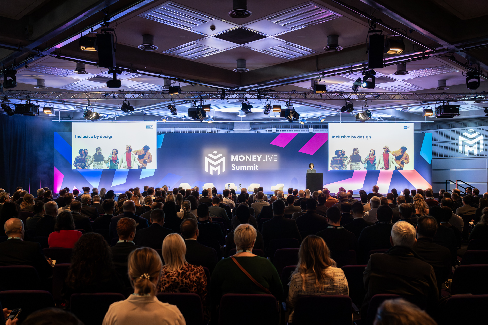 Large audience at professional event in QEII Centre with impactful staging, branding, and networking.