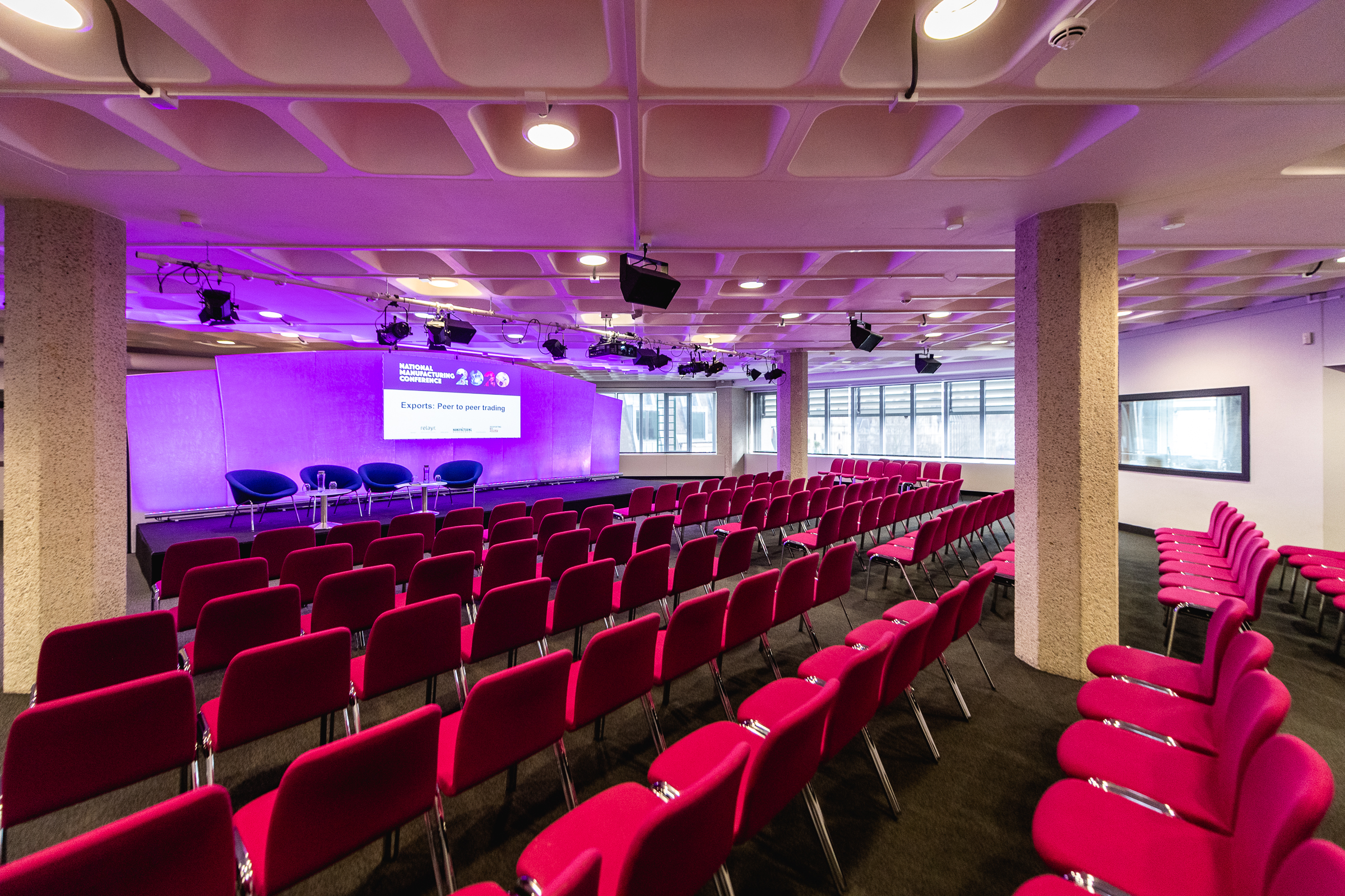 Event space in QEII Centre with pink seating, ideal for conferences and meetings.