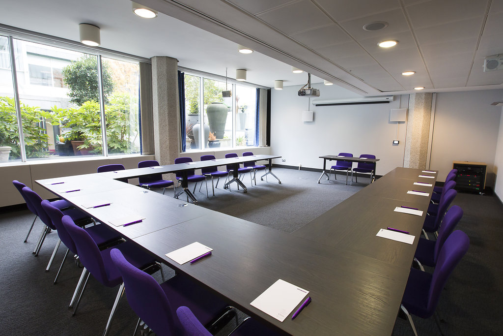 U-shaped meeting room with purple chairs, ideal for workshops and strategic planning.