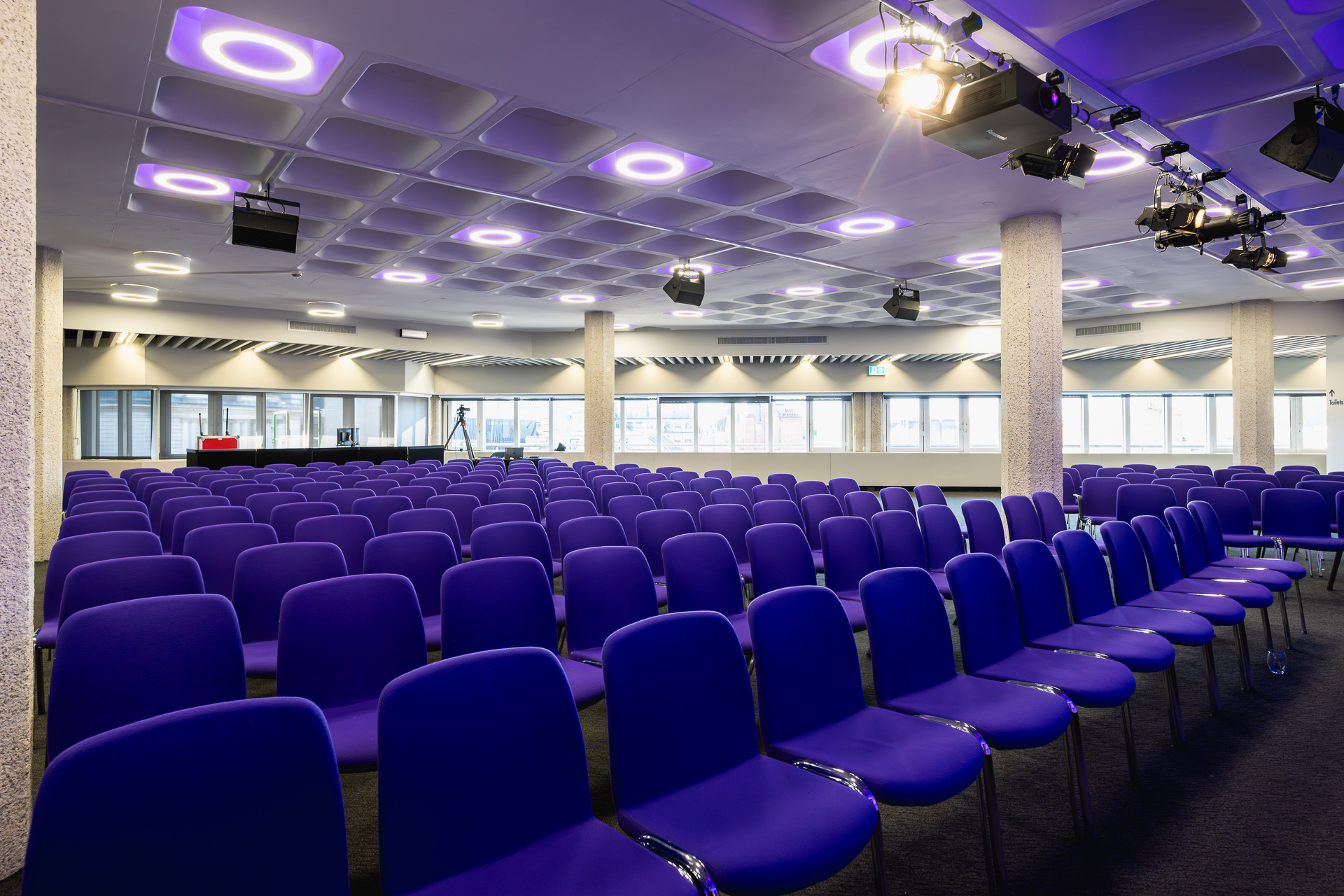 Modern event space in QEII Centre with vibrant purple chairs for conferences.