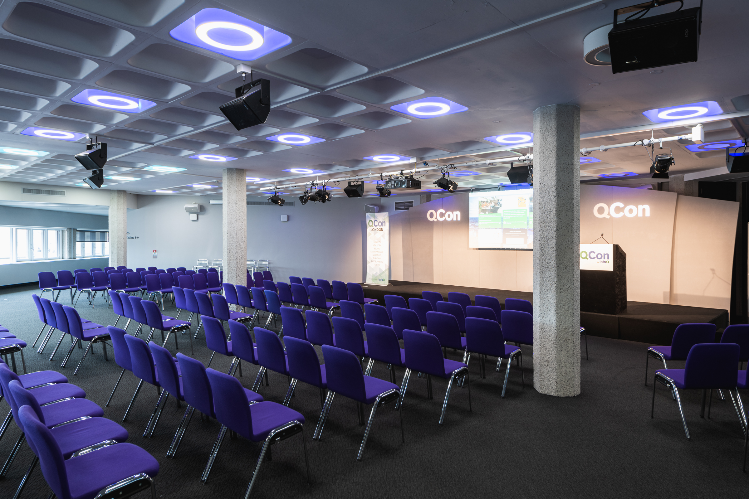 Modern conference room in QEII Centre with purple chairs for a tech event.