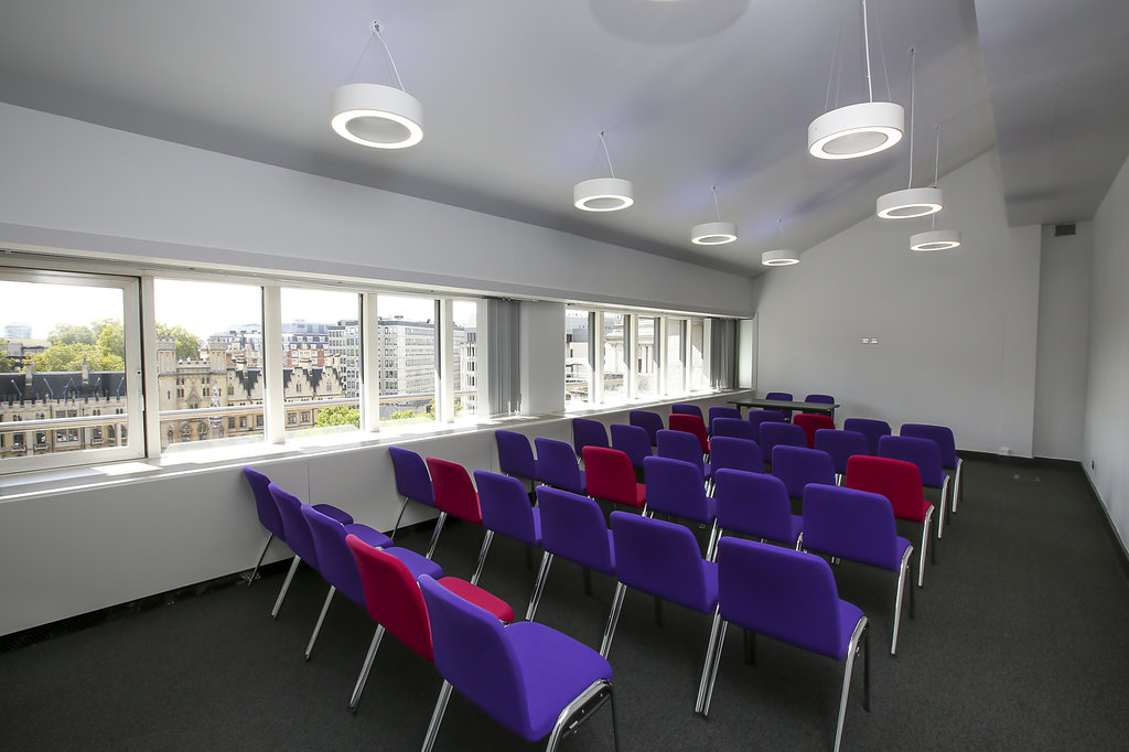 Modern meeting room in QEII Centre with colorful chairs, ideal for workshops and presentations.