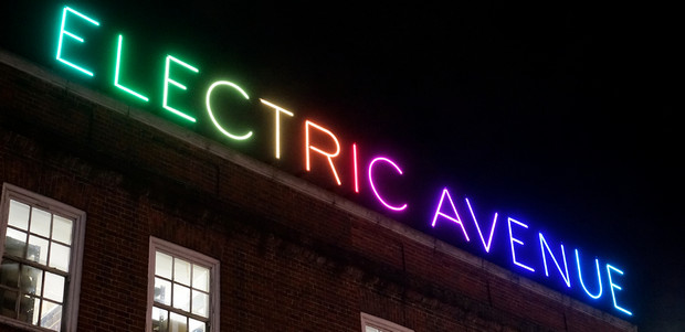 Vibrant "Electric Avenue" neon sign in lively event space for nightlife gatherings.