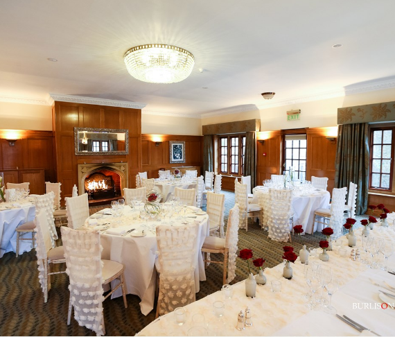 Elegant banquet room with white linens and red roses, perfect for weddings and corporate events.