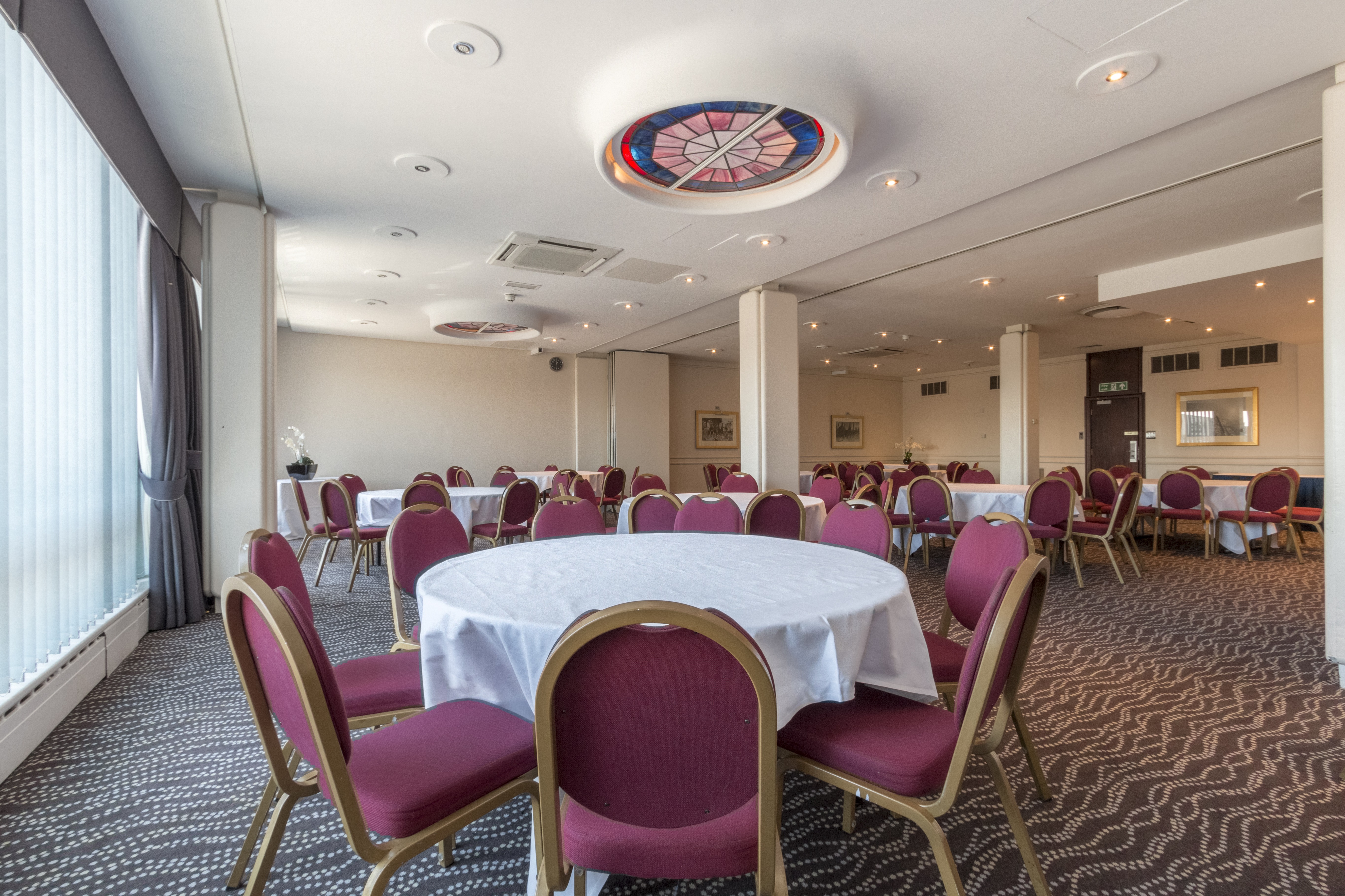 Print Room at Thistle London Heathrow: versatile event space with round tables for meetings.