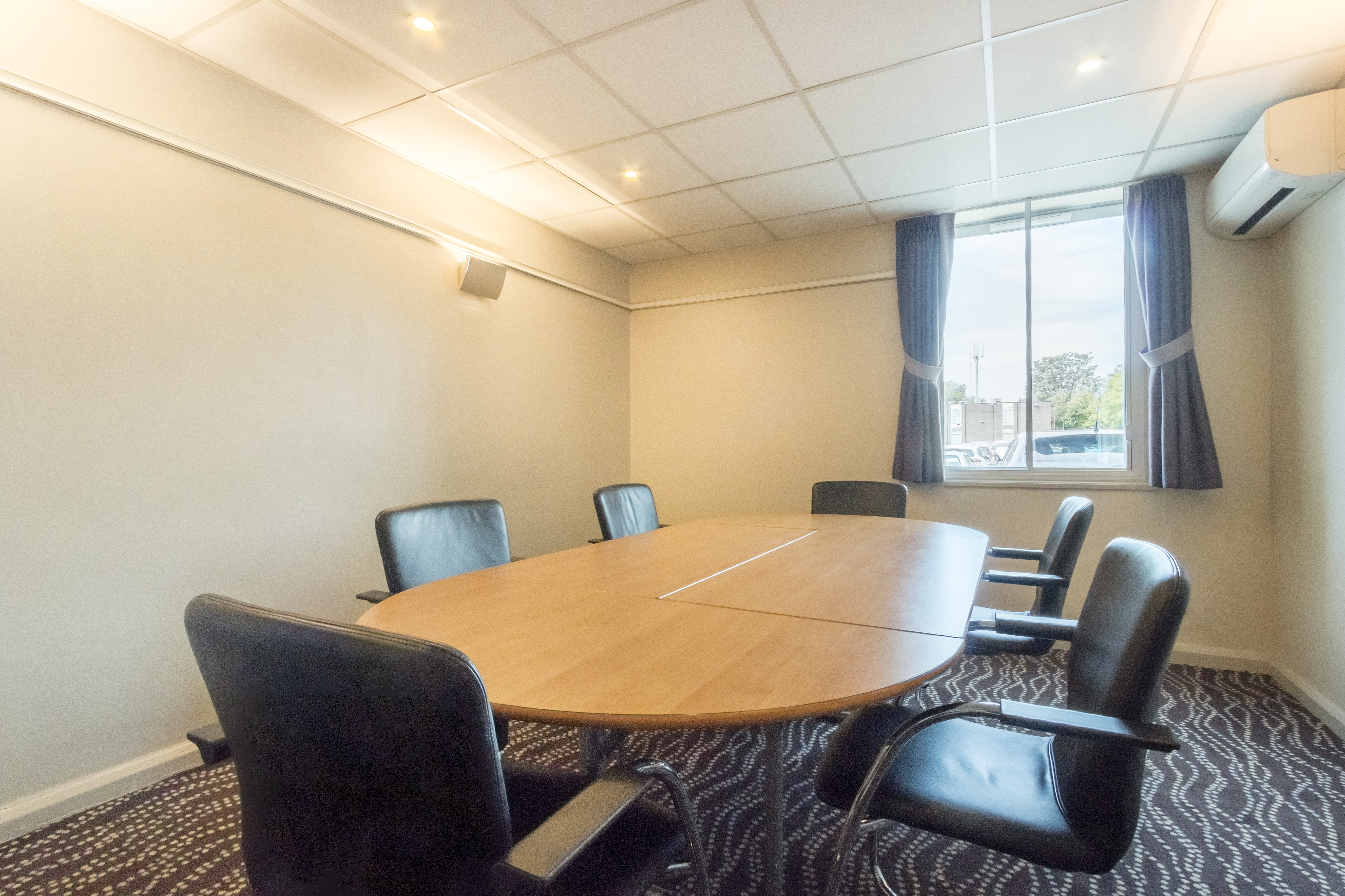 Syndicate Room 1 at Thistle London Heathrow: bright meeting space with round table and leather chairs.