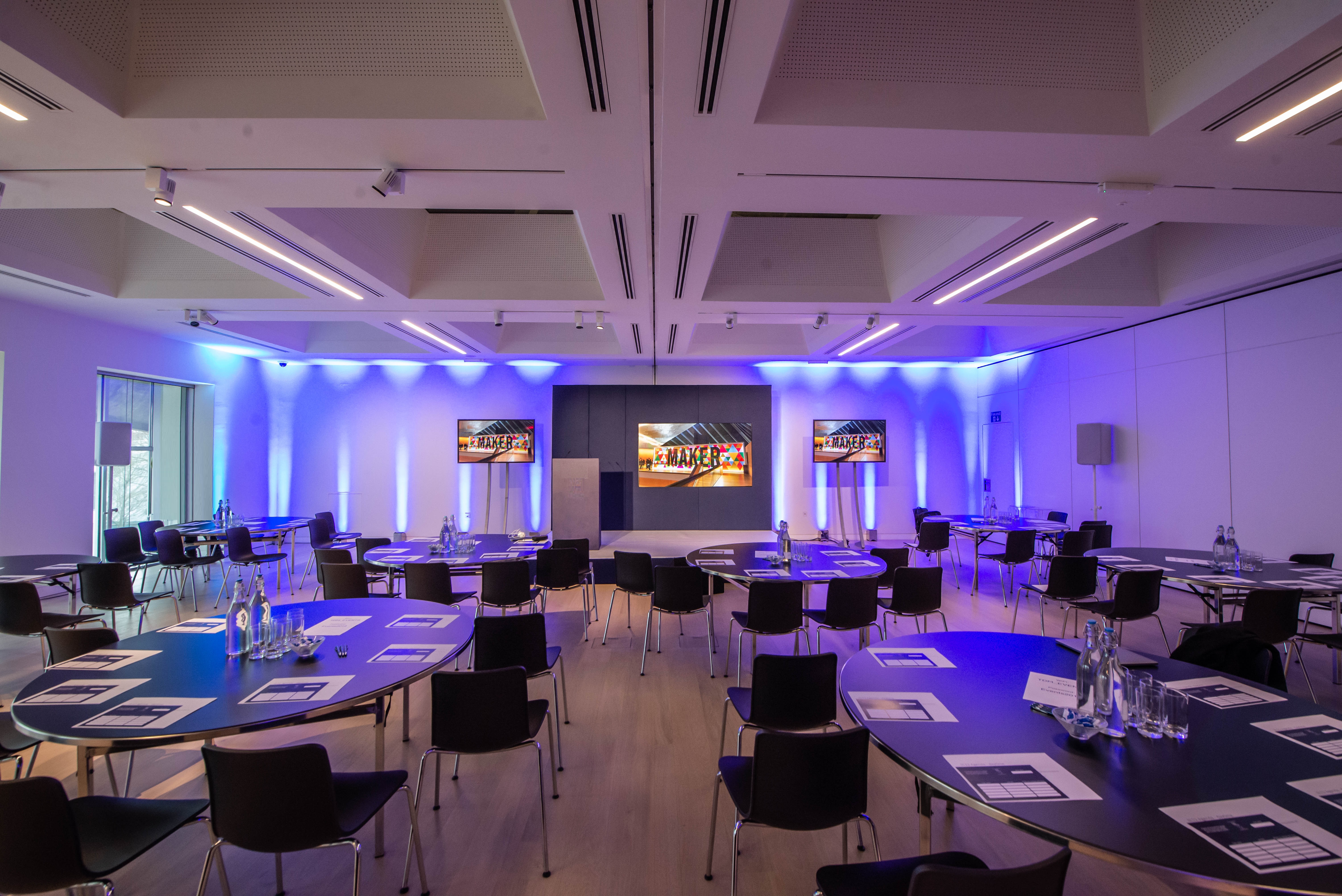Modern meeting space with round tables and blue lighting at Helene and Johannes Huth Gallery.