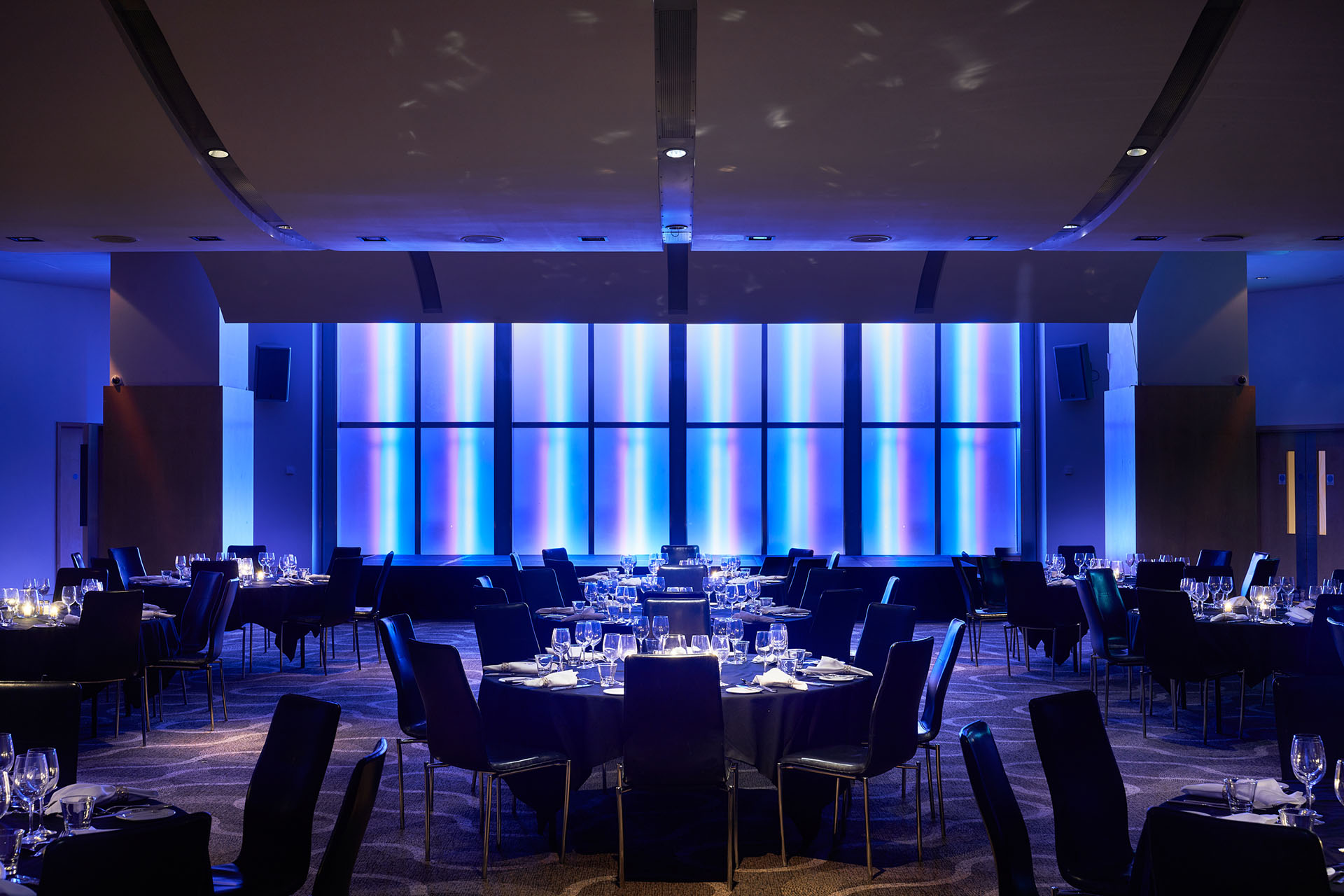 Elegant event space at The Cumberland Hotel with black table settings and blue lighting.