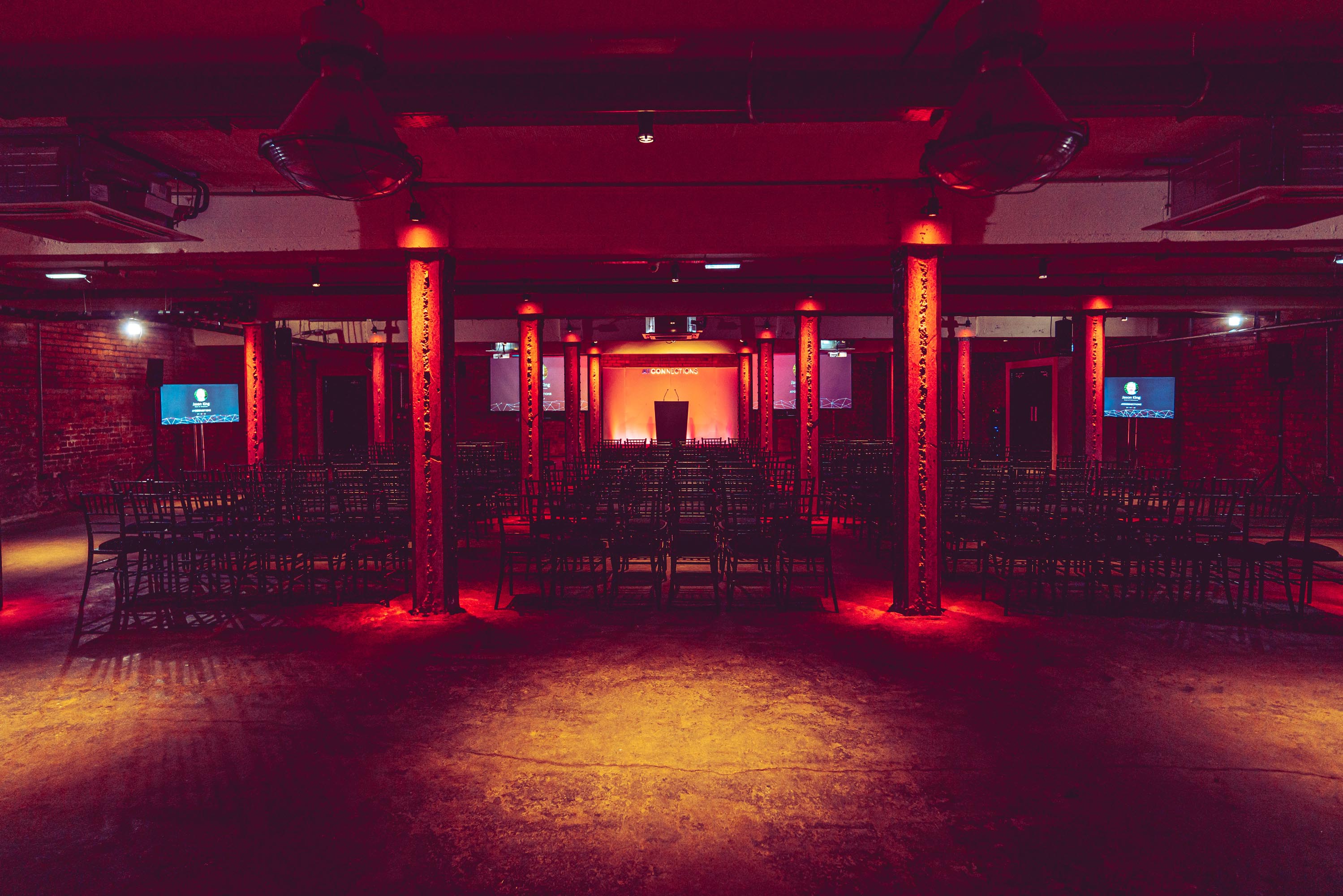 Versatile event space at Victoria Warehouse with dramatic lighting for conferences and workshops.
