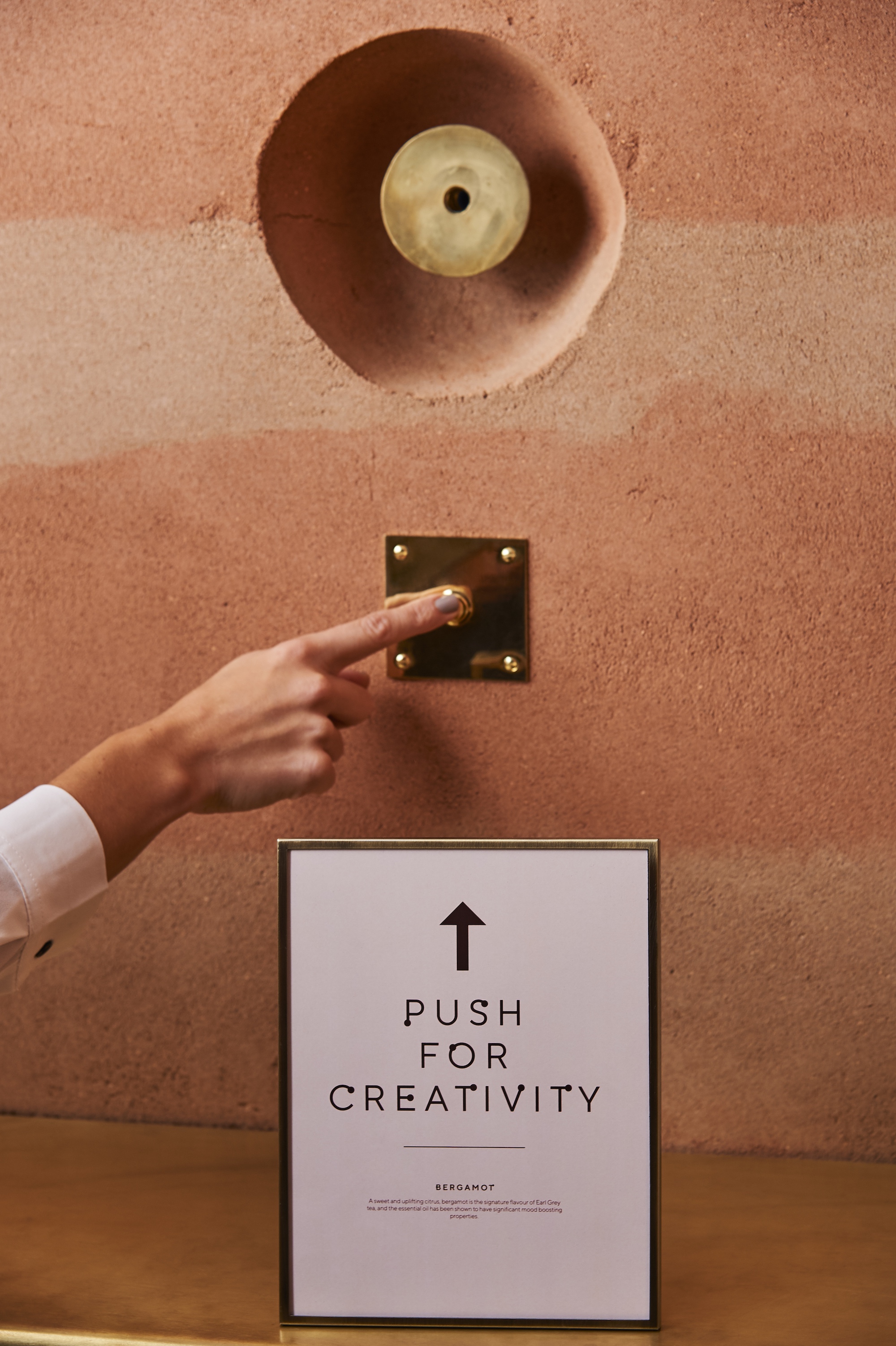 Hand pressing brass elevator button at AGORA, Hilton London Bankside for accessible events.