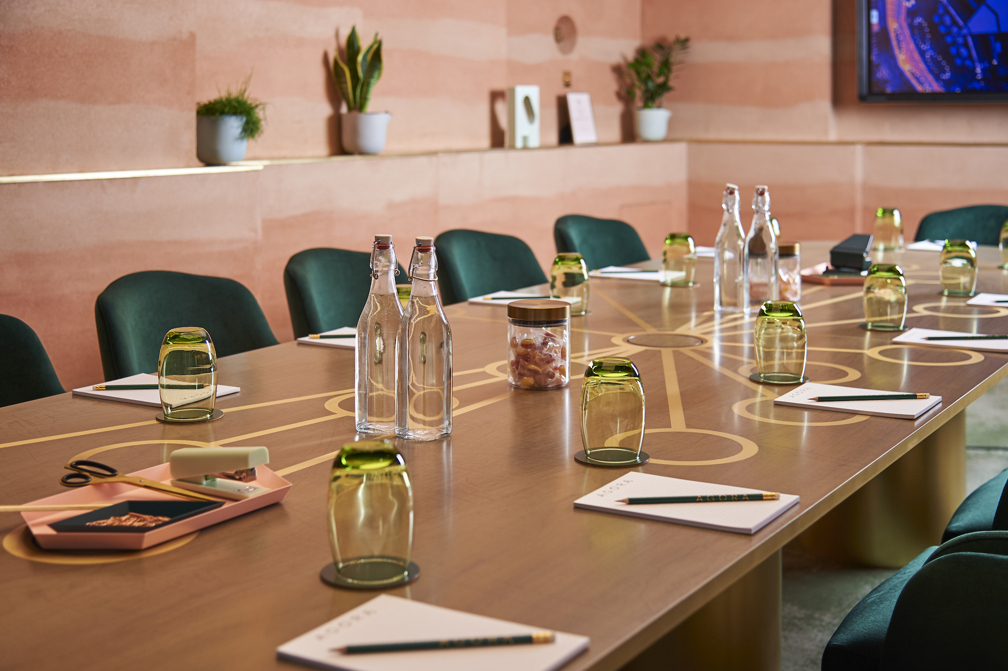 Modern meeting room at AGORA, Hilton London Bankside with wooden table and green chairs.