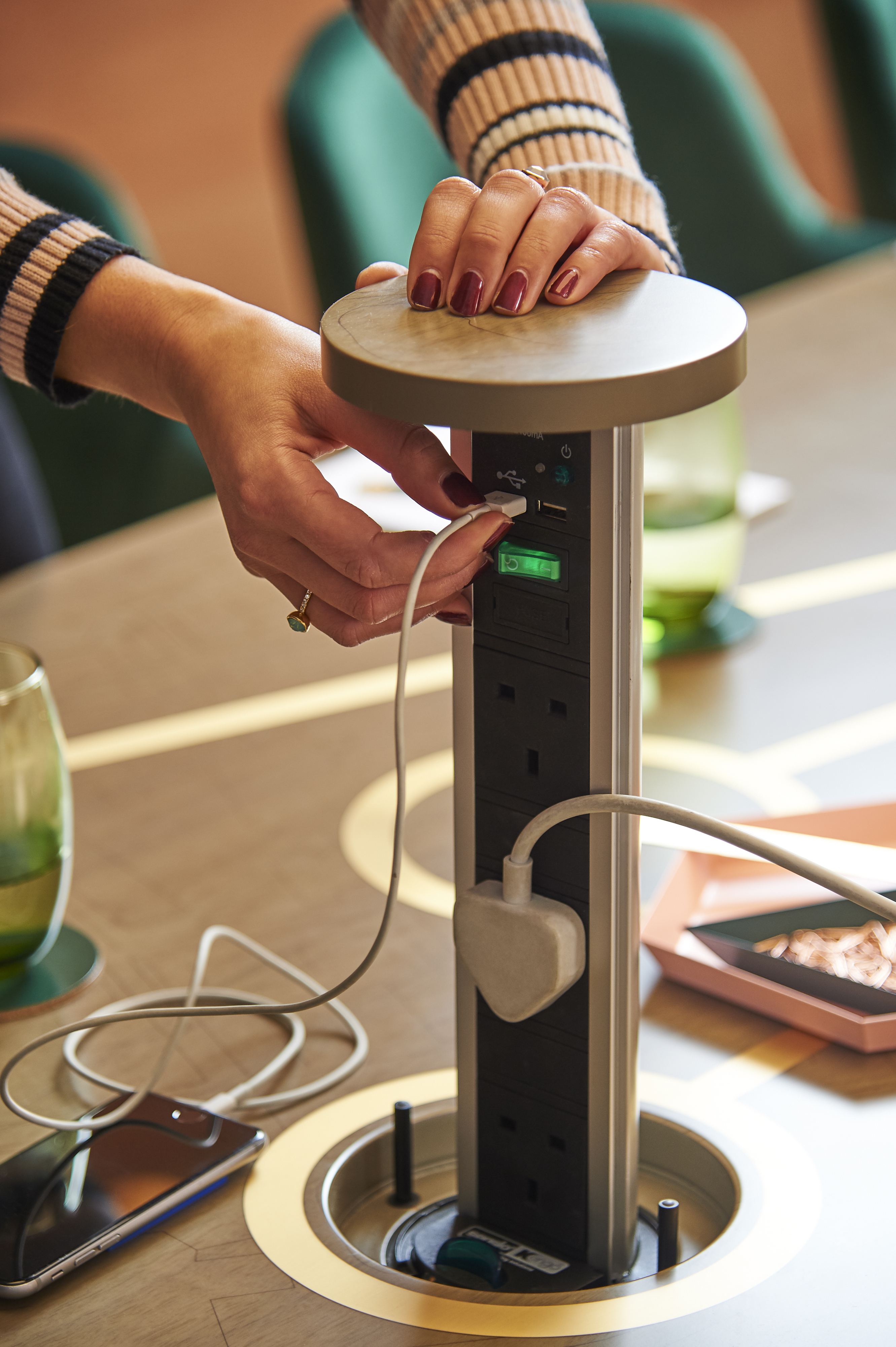 Close-up of a hand connecting a device to a lamp outlet at AGORA, Hilton London Bankside.