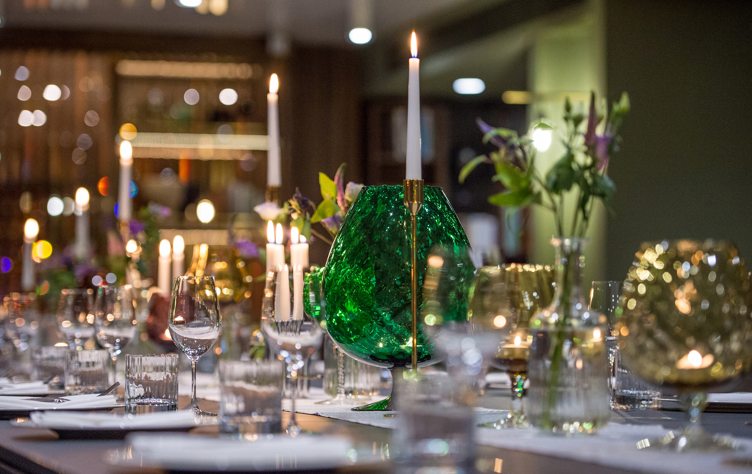 Elegant dining table with green glassware for gala dinners or intimate gatherings.