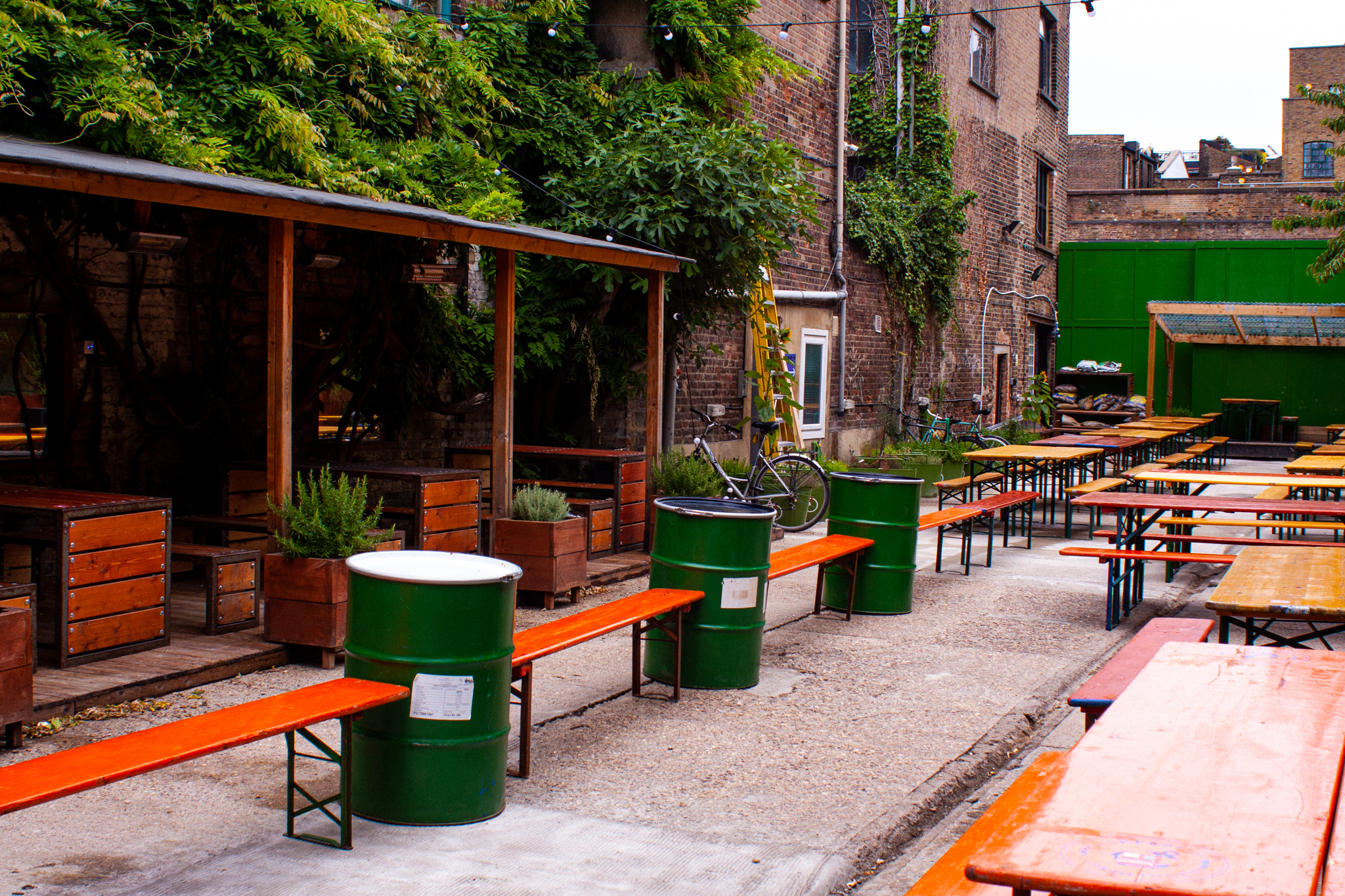 Outdoor event space at Strongroom Bar with rustic tables and vibrant greenery.