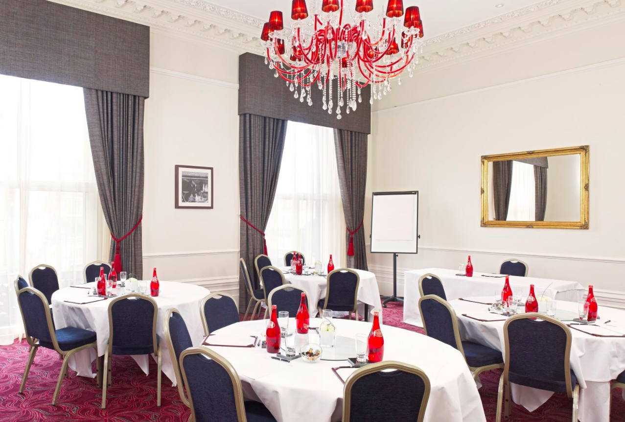Elegant meeting room with round tables, red accents, ideal for workshops and gatherings.