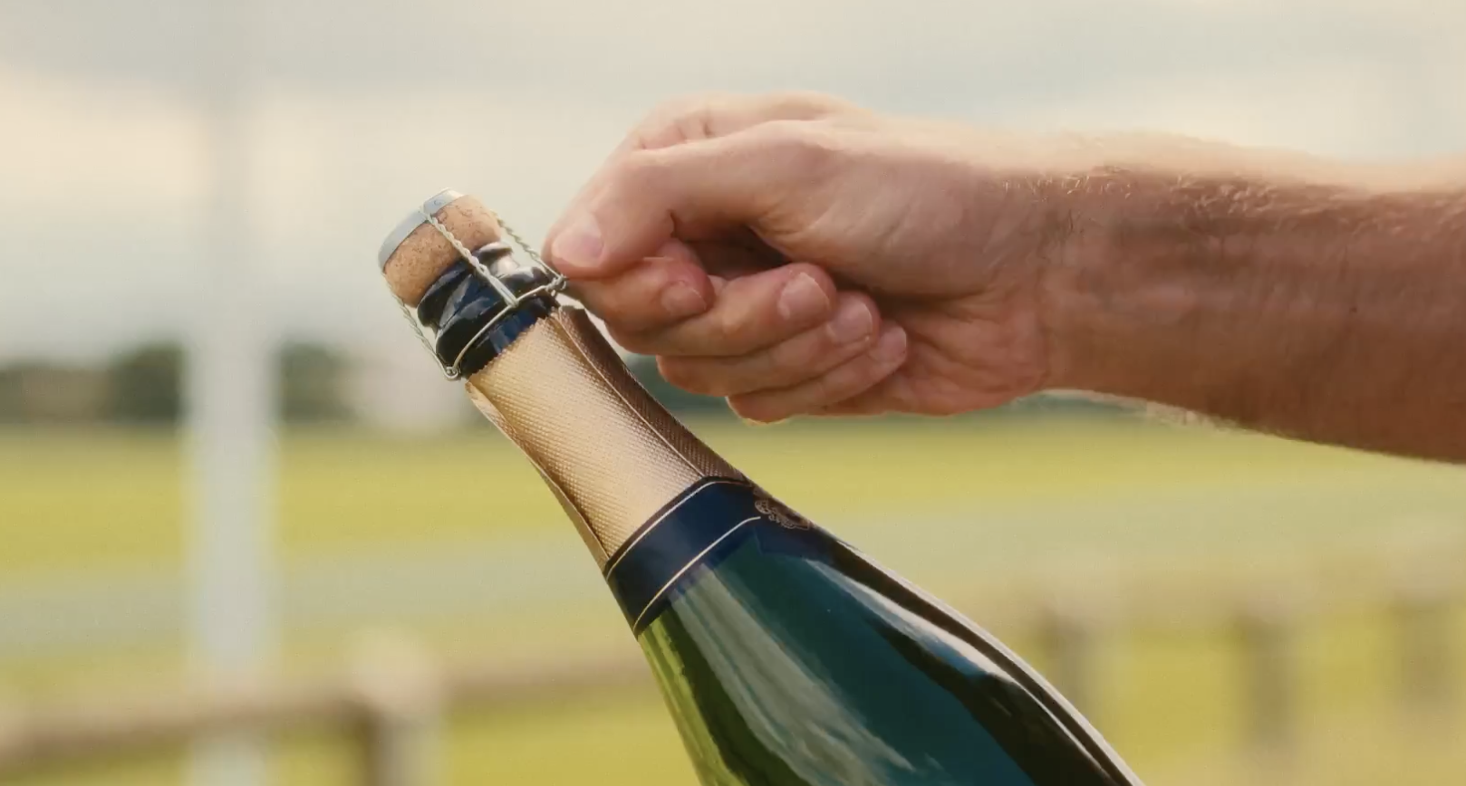 Hand uncorking champagne at Emsworth Polo Grounds, symbolizing celebration and events.