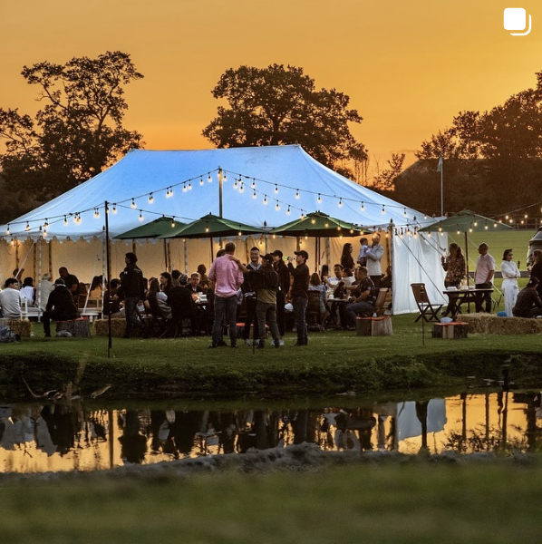 Outdoor polo event under a tent with string lights at sunset in Emsworth.