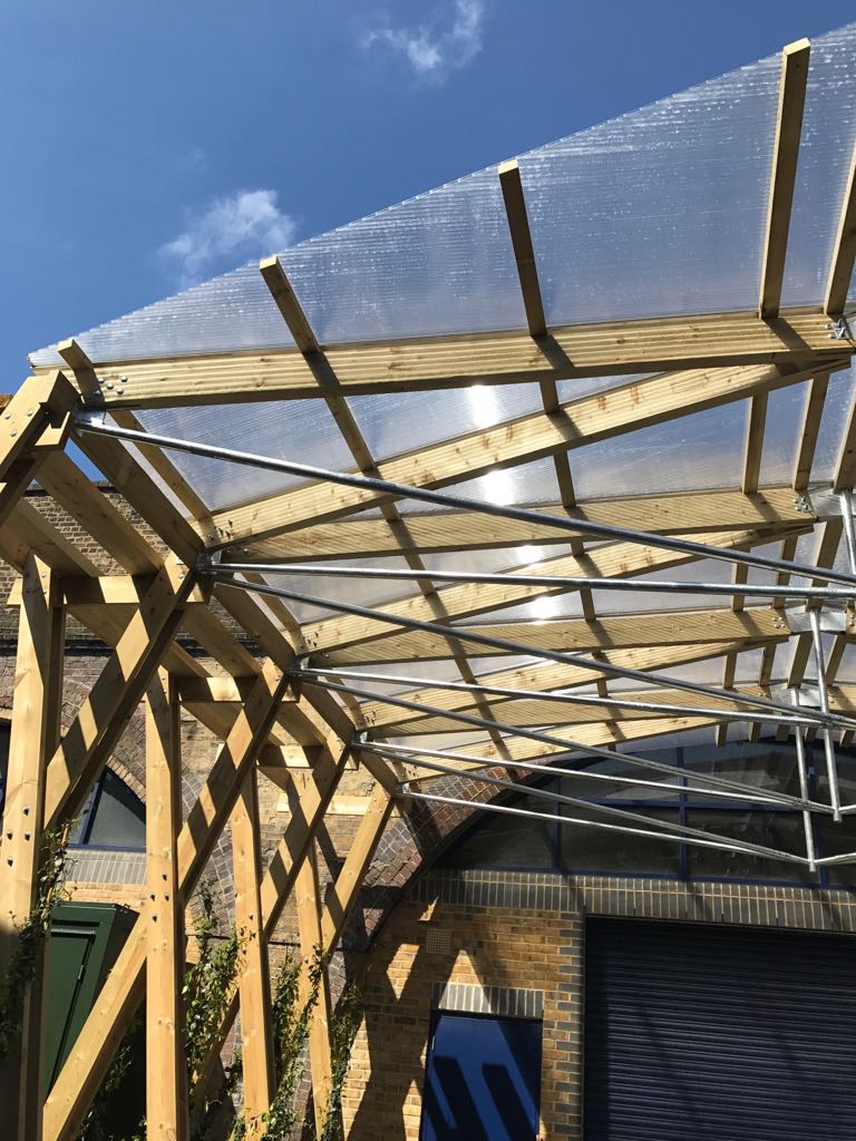 Partially constructed outdoor venue with wooden frame and clear roofing for events.