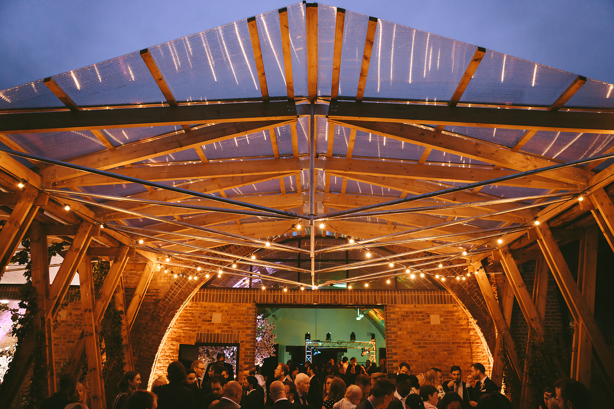 Elegant event space with wooden structure and transparent roof for networking and celebrations.