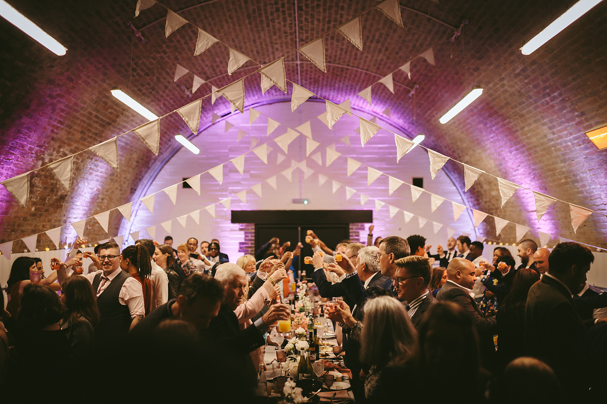 Vibrant event space at AMP Studios with guests toasting, ideal for celebrations and gatherings.