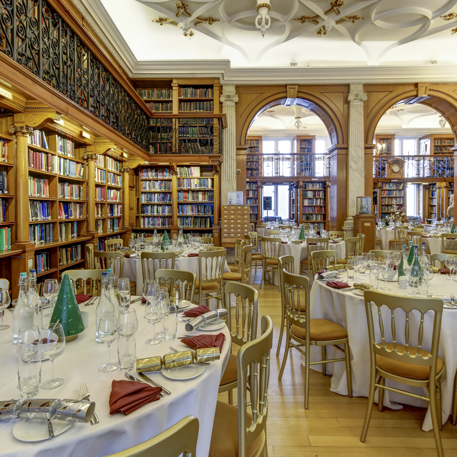 Elegant library event space with round tables for formal dinners, ideal for corporate gatherings.