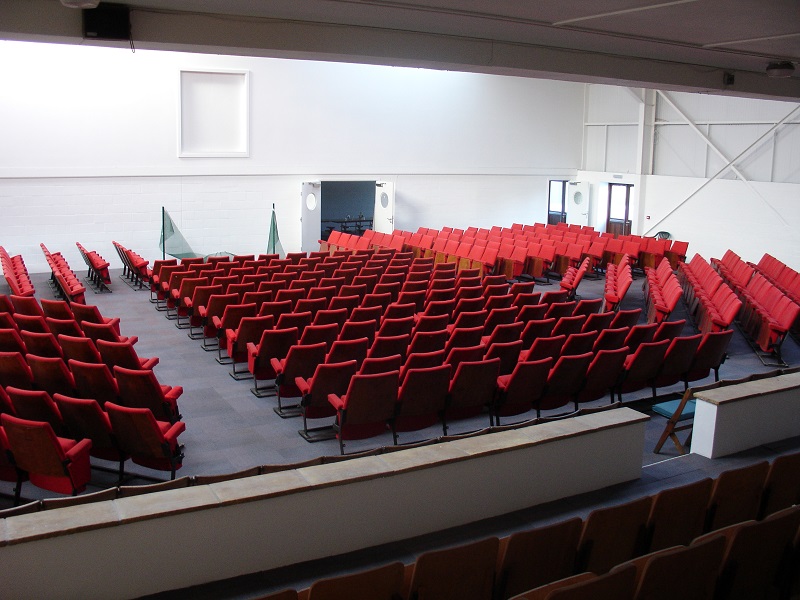 Spacious conference hall with red chairs, ideal for events and workshops.