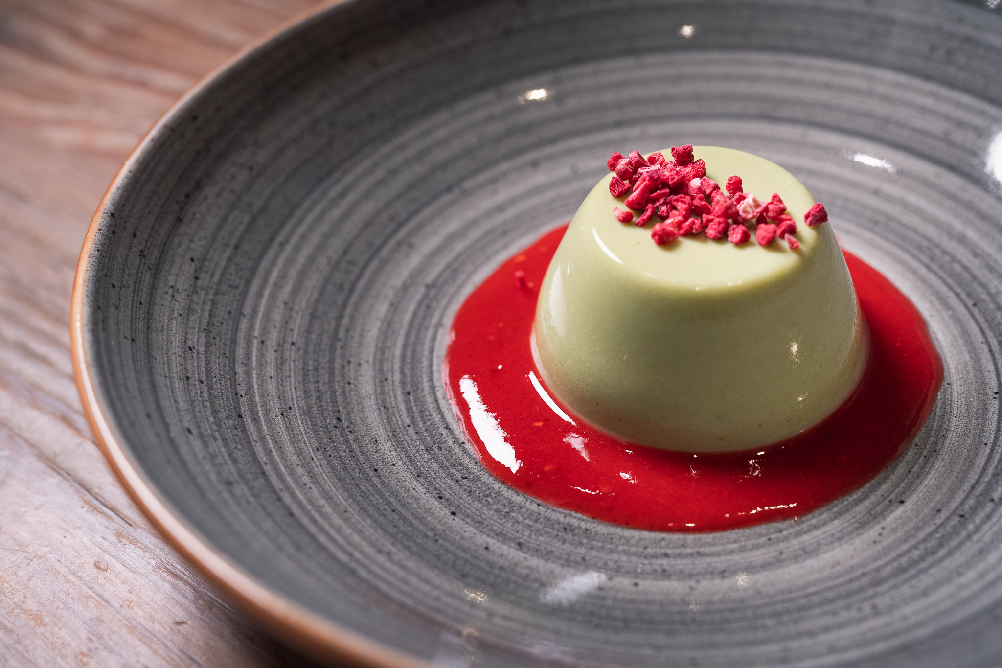 Green panna cotta dessert with raspberry coulis at Wild Heart Bar, Soho event catering.