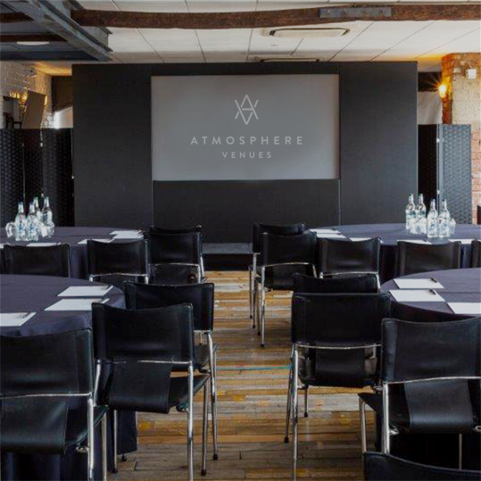 Modern meeting room at Skyloft, with round tables and presentation screen for corporate events.