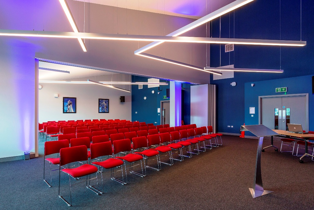 Modern event space with red chairs at Imperial War Museum North for conferences and workshops.