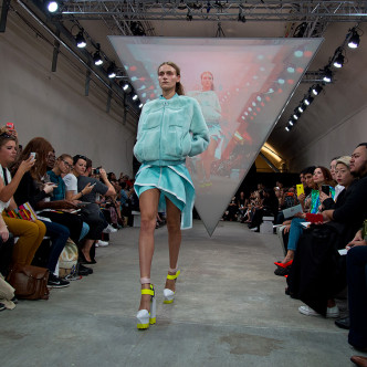 Model on runway at The Big Black One fashion event with triangular projection.