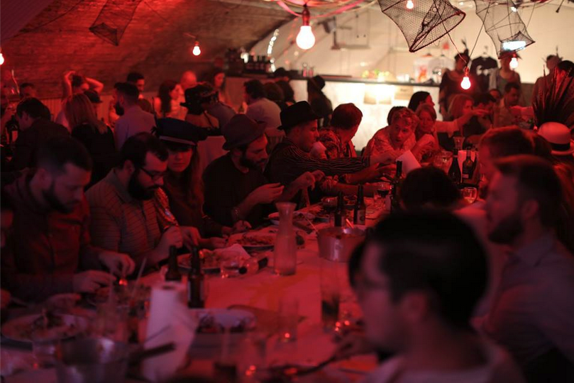 Vibrant dining event at The Vaults with warm lighting and communal table for networking.