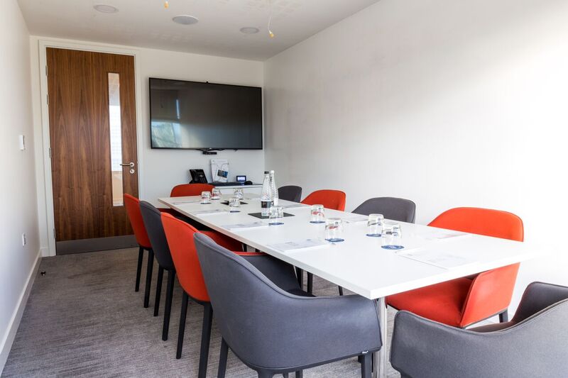 Modern meeting room at The Royal Pharmaceutical Society with vibrant orange chairs.