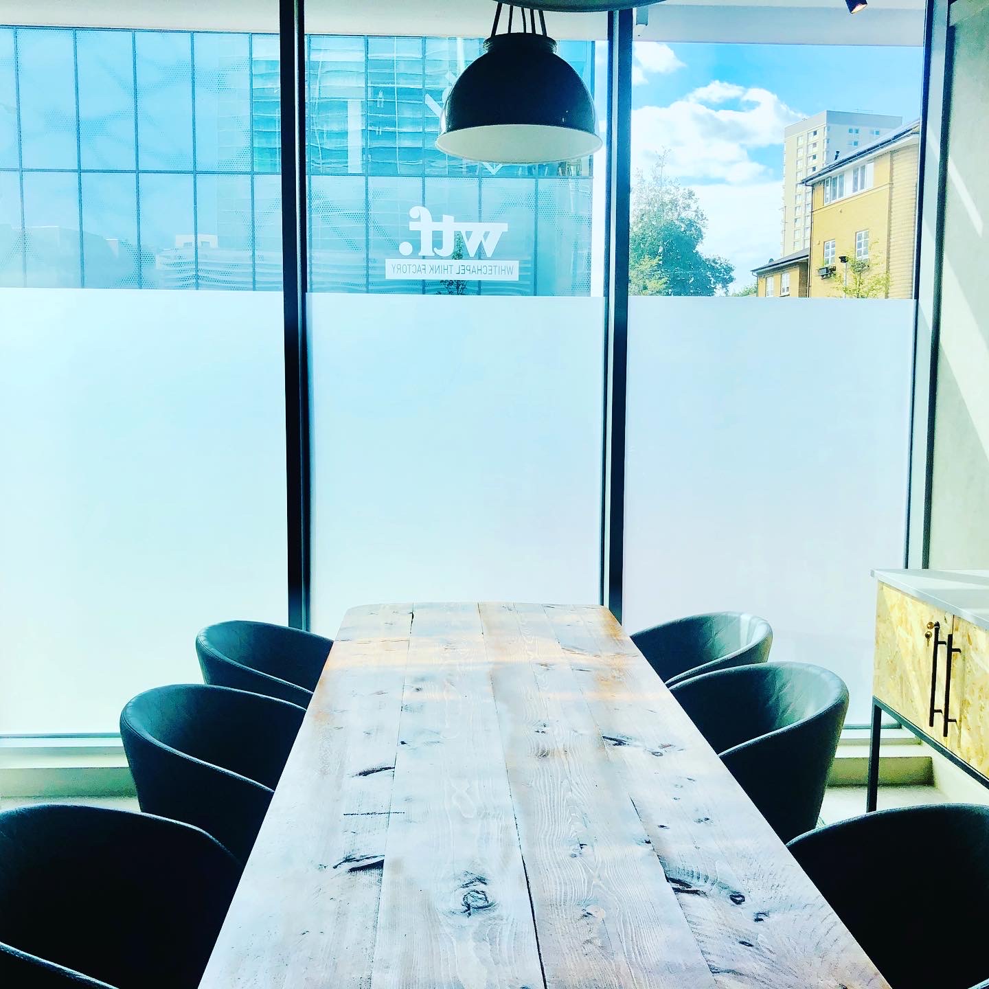 Modern meeting space at Holiday Inn Whitechapel with wooden table and natural light.