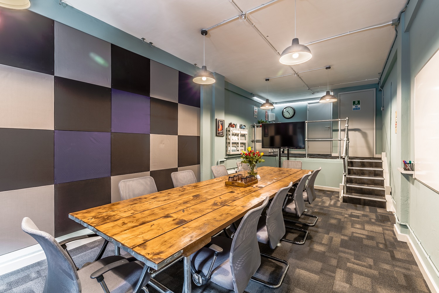 Modern meeting room with long wooden table, ideal for presentations and collaboration.