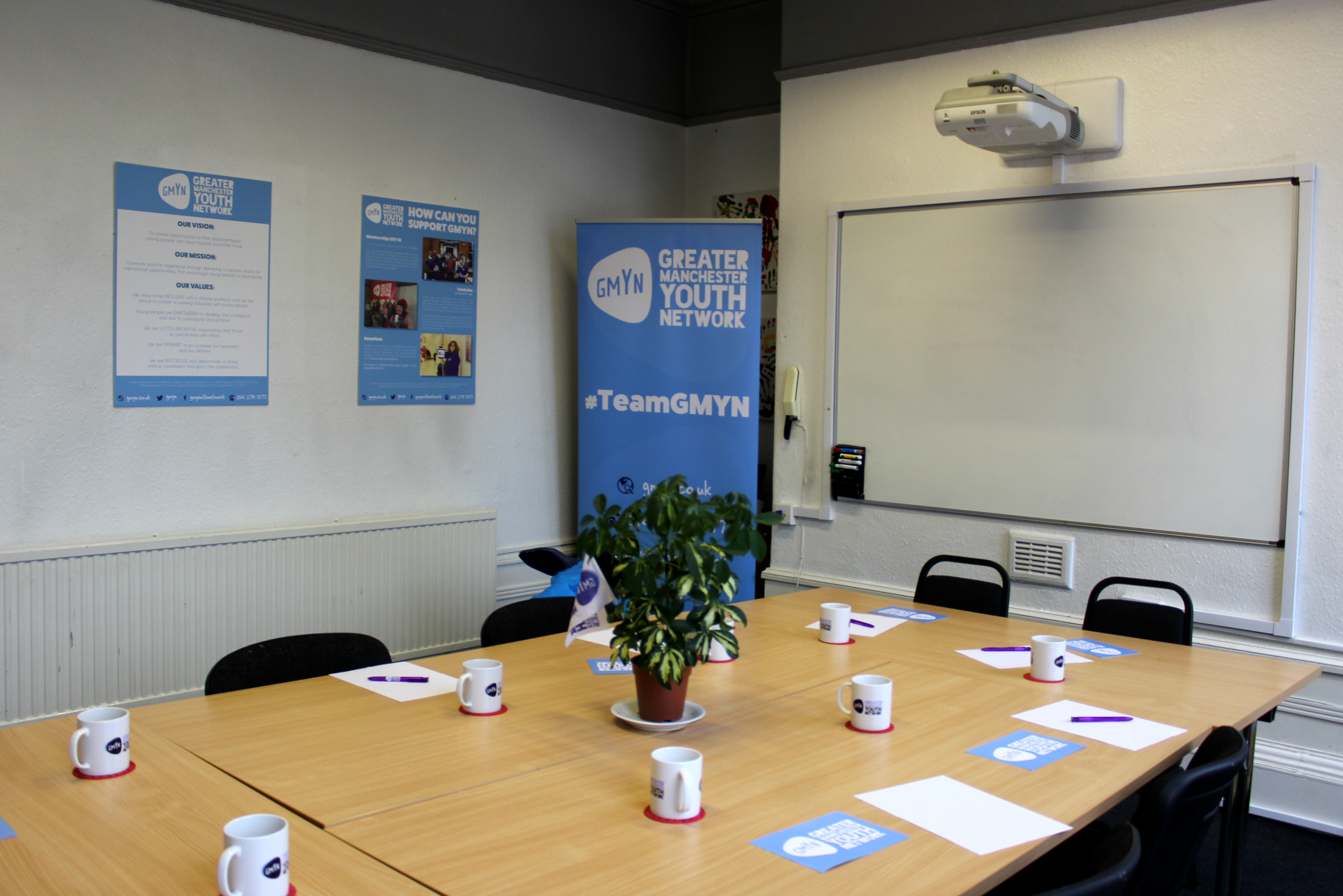 Meeting room setup with mugs and notepads for collaborative sessions and presentations.