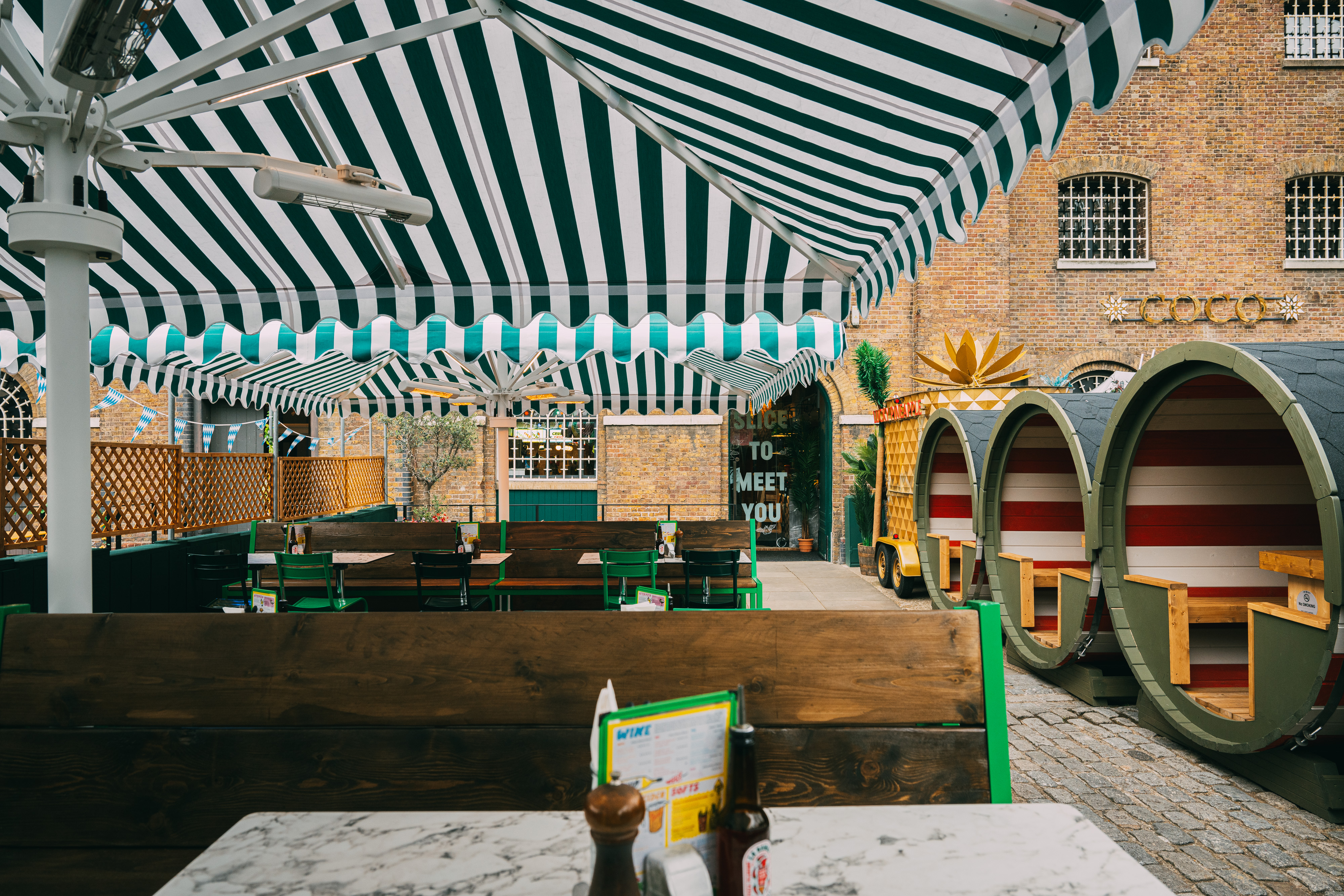 Vibrant outdoor event space at The Pizza Playground with striped canopies for gatherings.