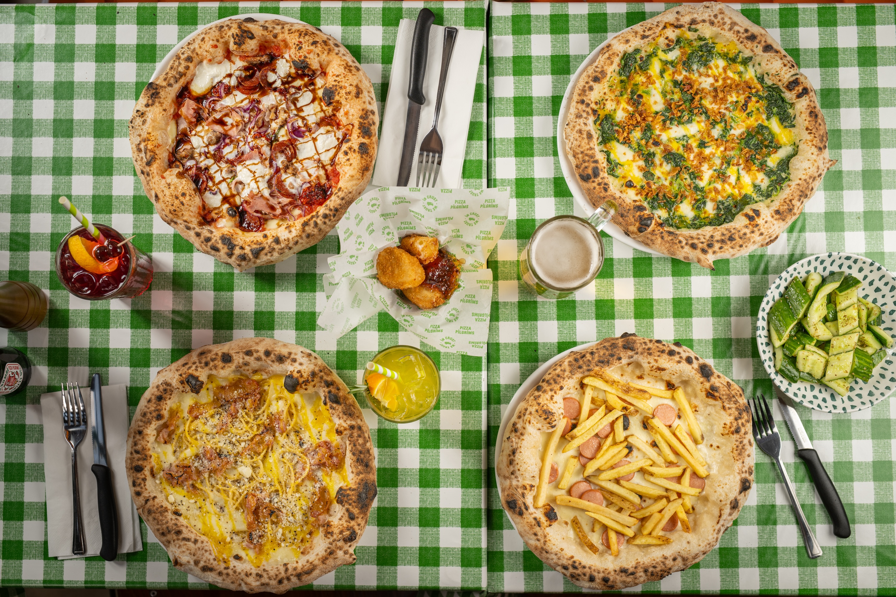 Gourmet pizzas on checkered tablecloth at Pizza Playground for casual dining events.