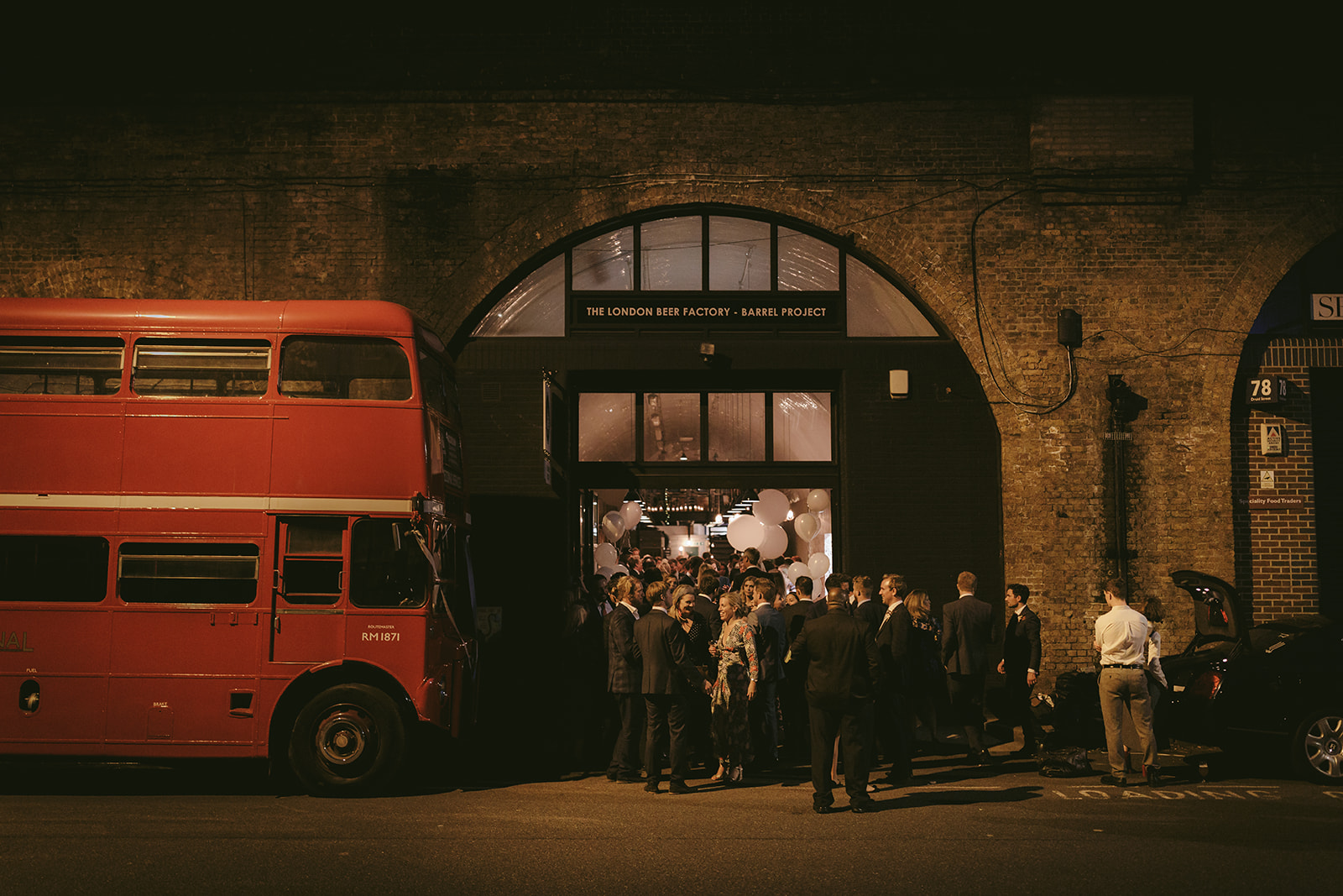 Vibrant event entrance with a red double-decker bus at The Barrel Project venue.