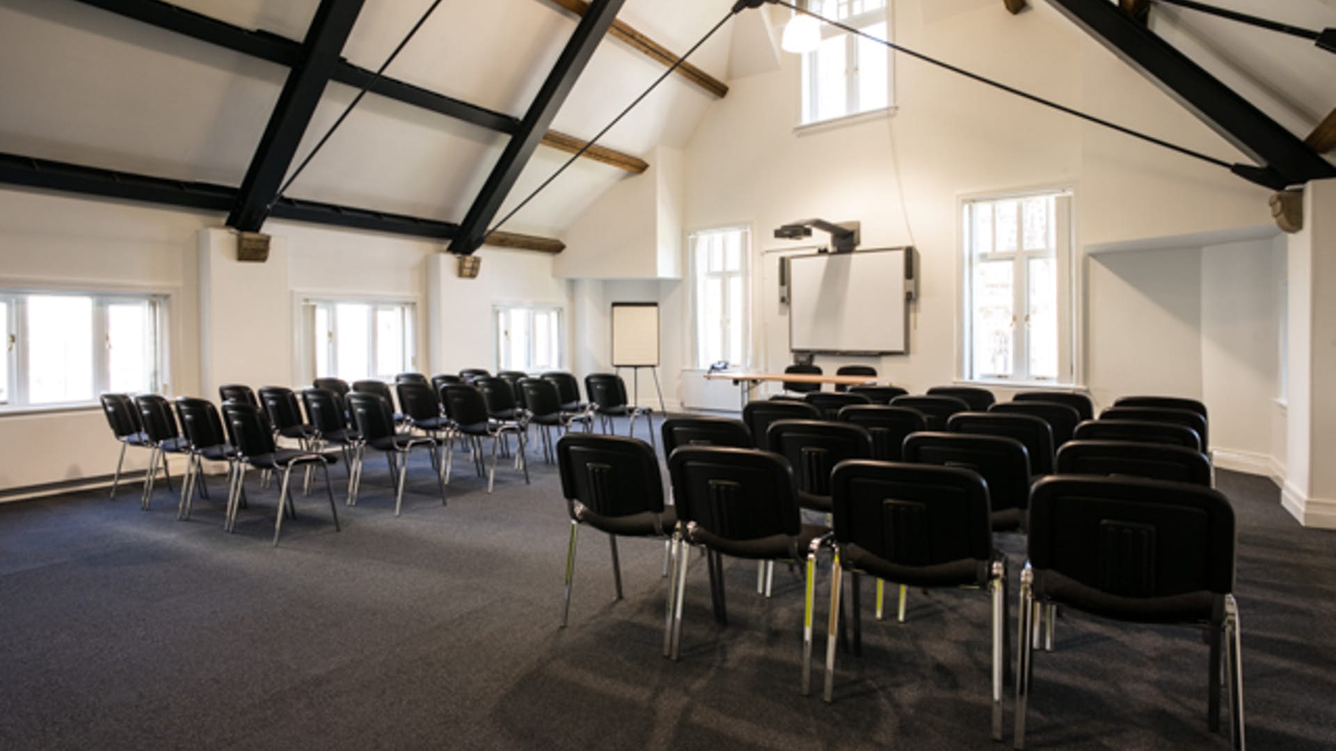 "Bright conference room with black chairs and large screen for presentations at Manchester Cathedral."
