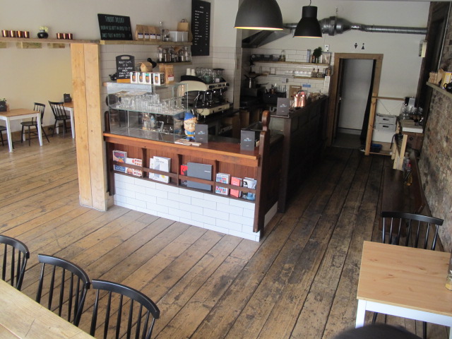 Cozy café venue with warm wooden floors, ideal for intimate meetings and events.