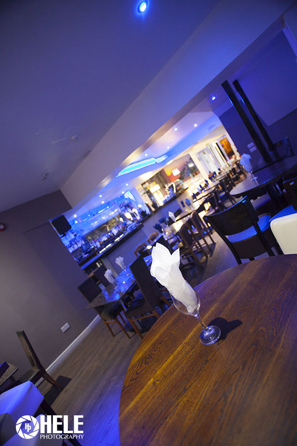 Modern event space in Santorini Restaurant with sleek bar and ambient blue lighting.