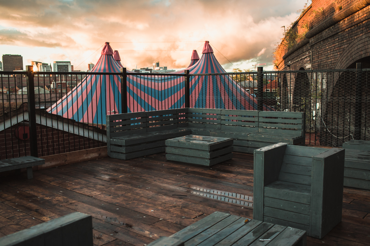 Rooftop venue with wooden deck and circus tents, ideal for creative outdoor events.