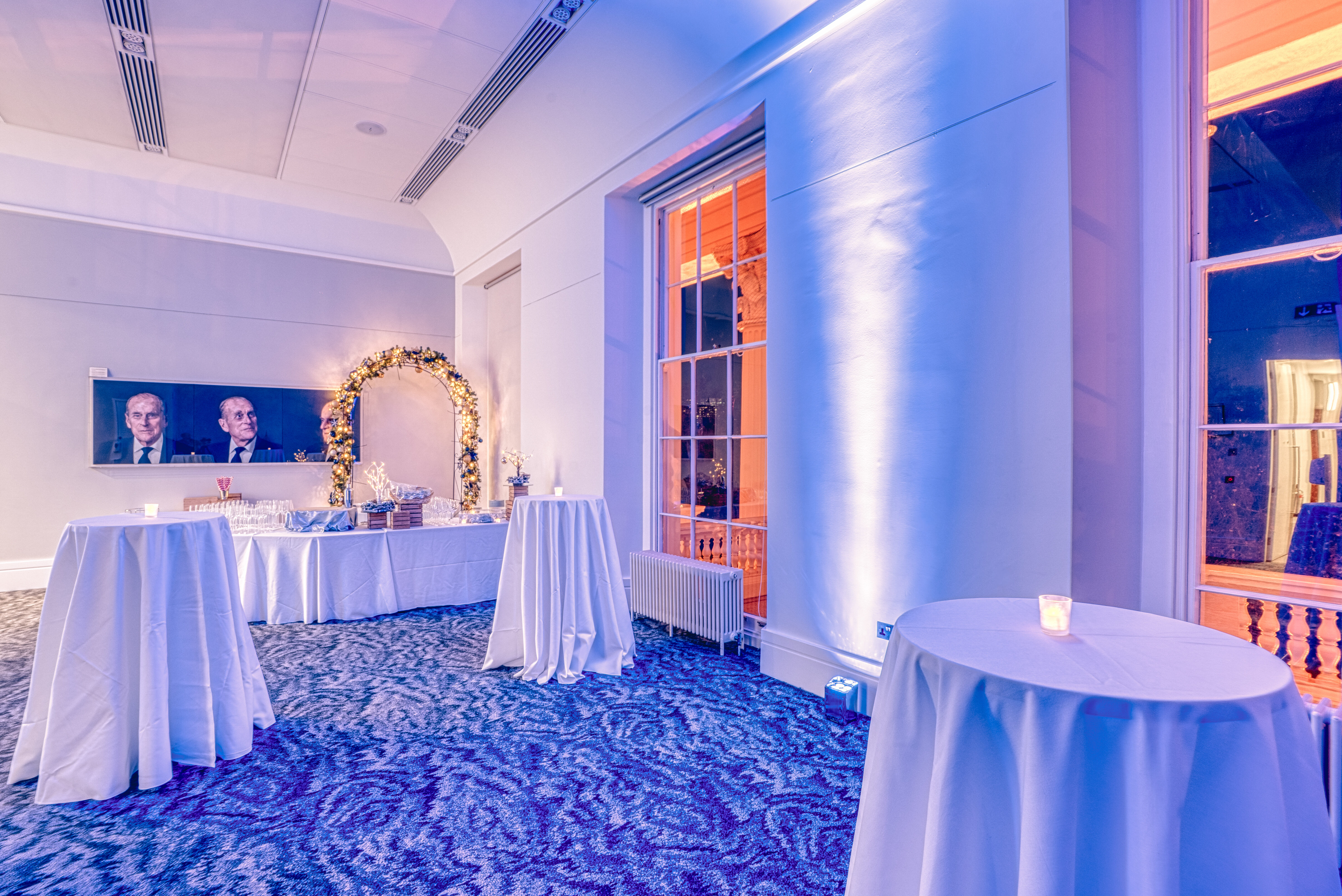 Christmas party at Prince Philip House with elegant blue lighting and high-top tables.