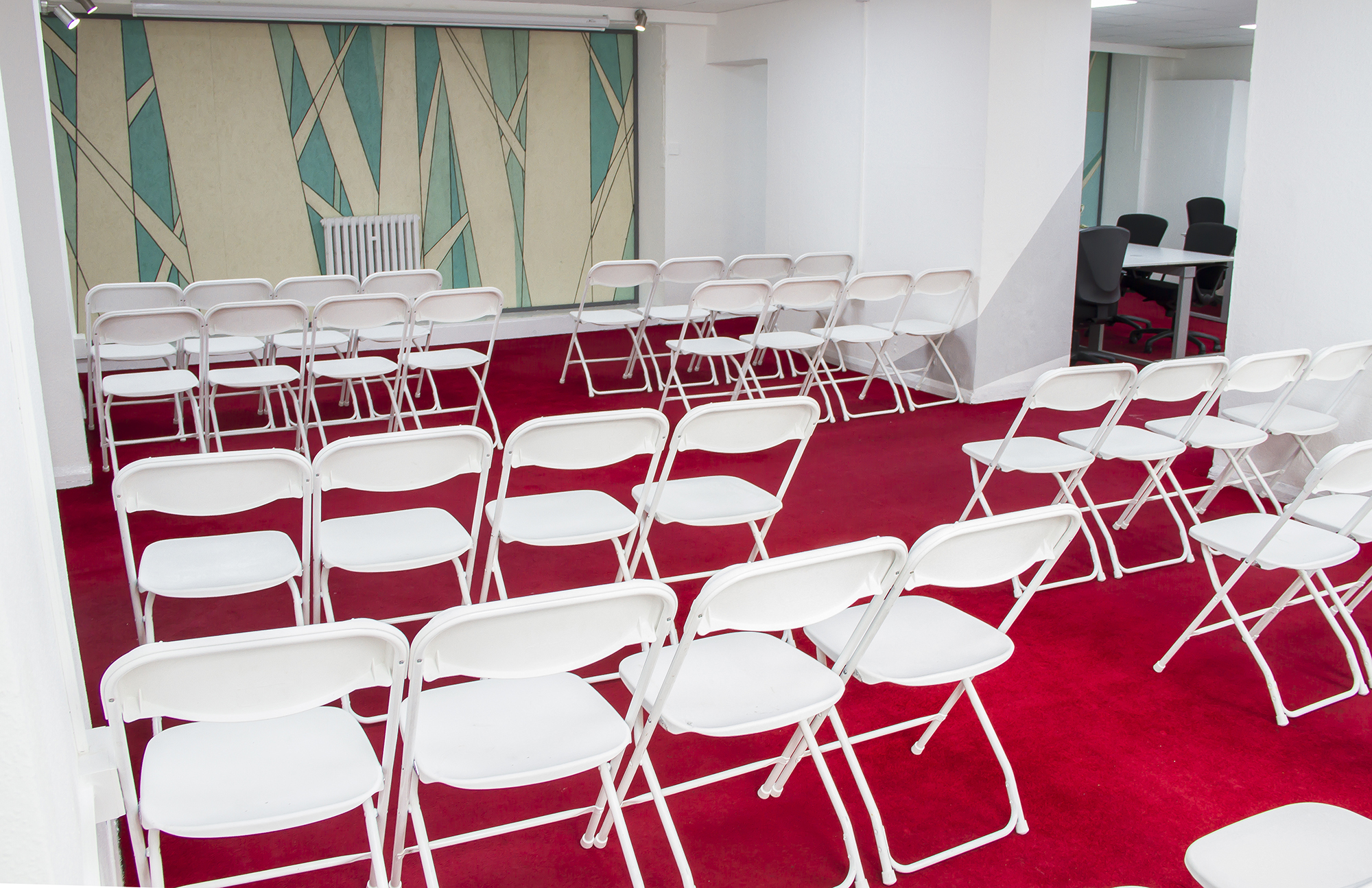 Versatile Events Space with white chairs, ideal for workshops and presentations.